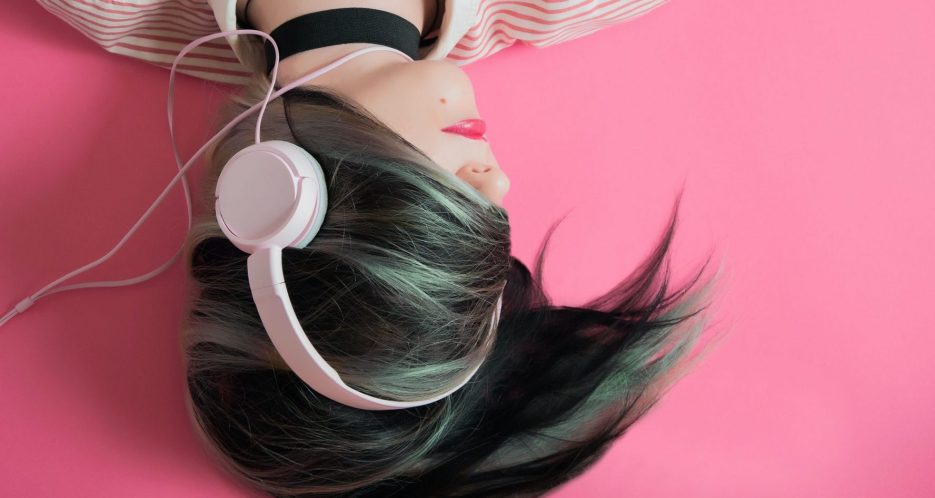 Ein Mädchen das am Boden liegt und mit Kopfhörer Musik hört