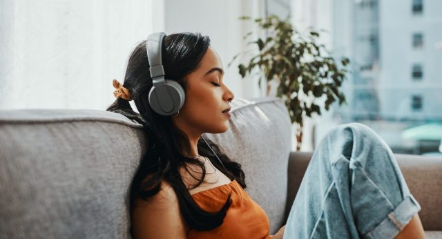 Woman with headphones sitting on a couch